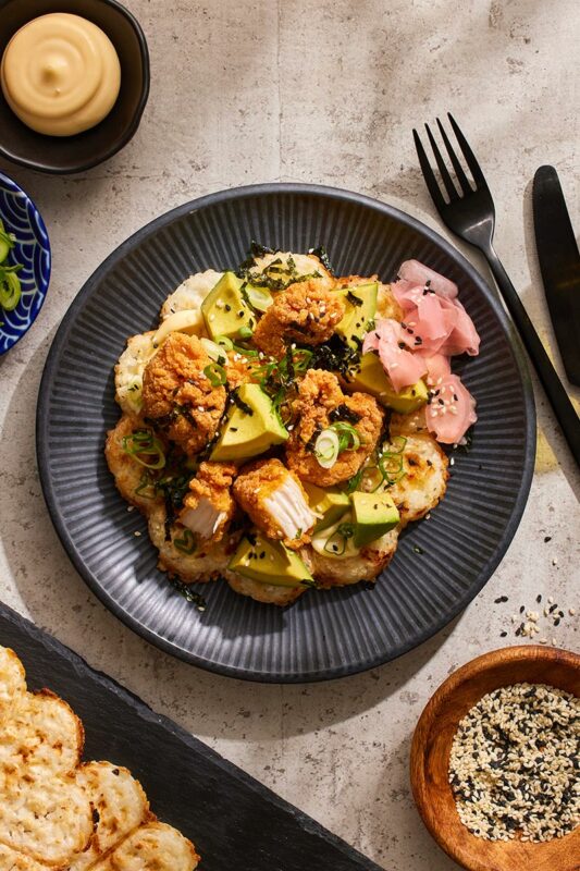 Plated dish with fried food, vegetables, and a side of bread on a textured surface.