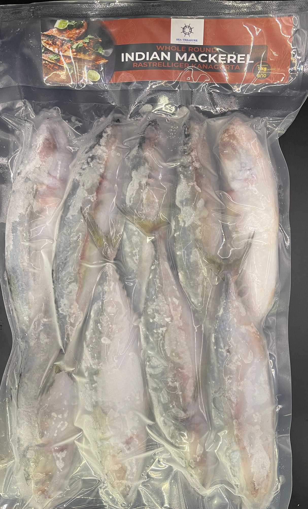 Packaged Indian mackerel fish with a clear plastic wrap on a black background