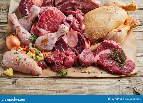 Assorted raw meats including chicken, beef, and pork on a wooden surface.