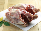 Raw chicken carcass on a cutting board with a lemon and bay leaves.