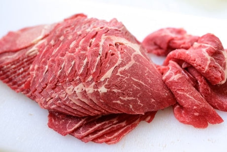 Raw beef slices on a white cutting board
