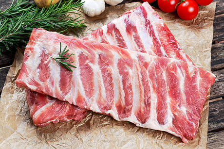 Raw pork belly with rosemary on a rustic wooden surface